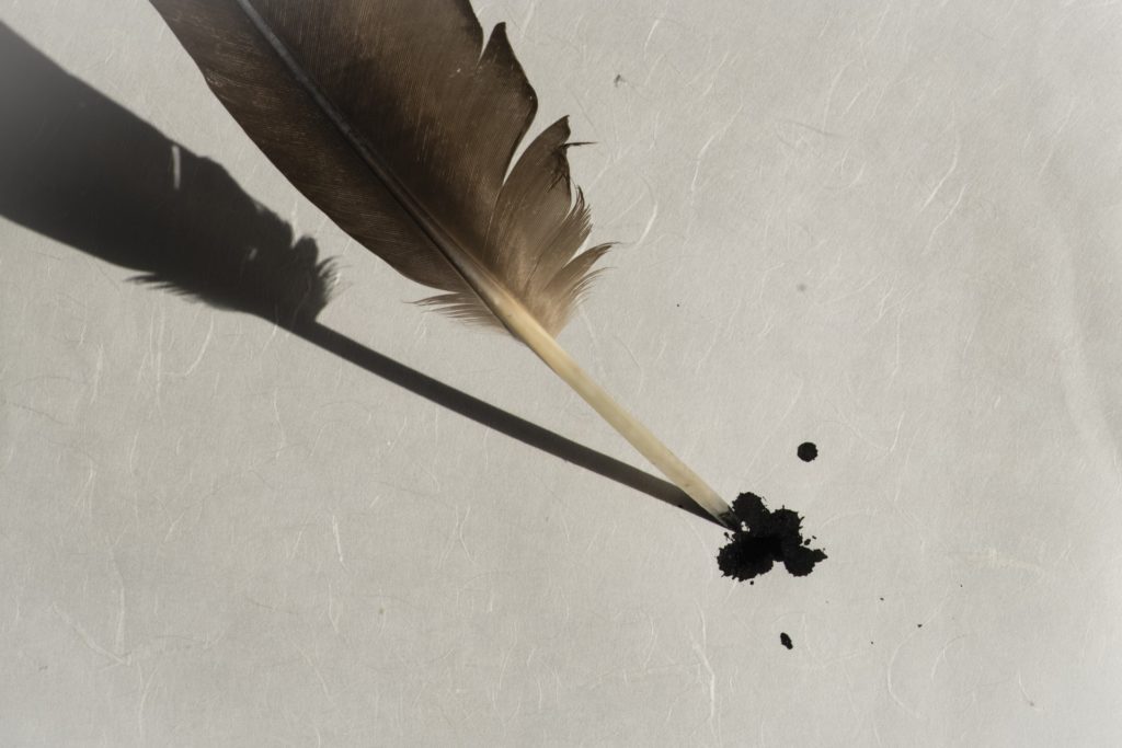 Imagen de una pluma, que ha dejado una mancha de tinta