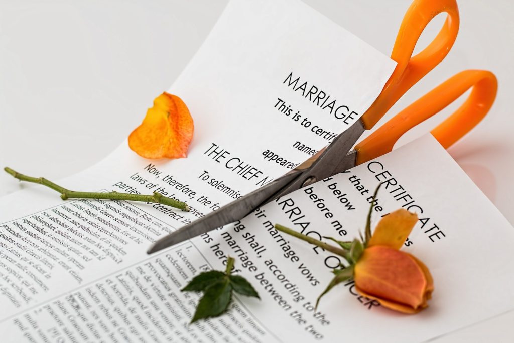 Imagen de un certificado matrimonial y unas rosas amarillas, siendo cortados con una tijeras