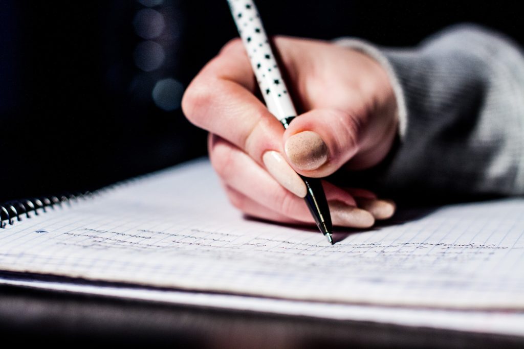 Imagen de una persona escribiendo con un bolígrafo sobre un cuaderno